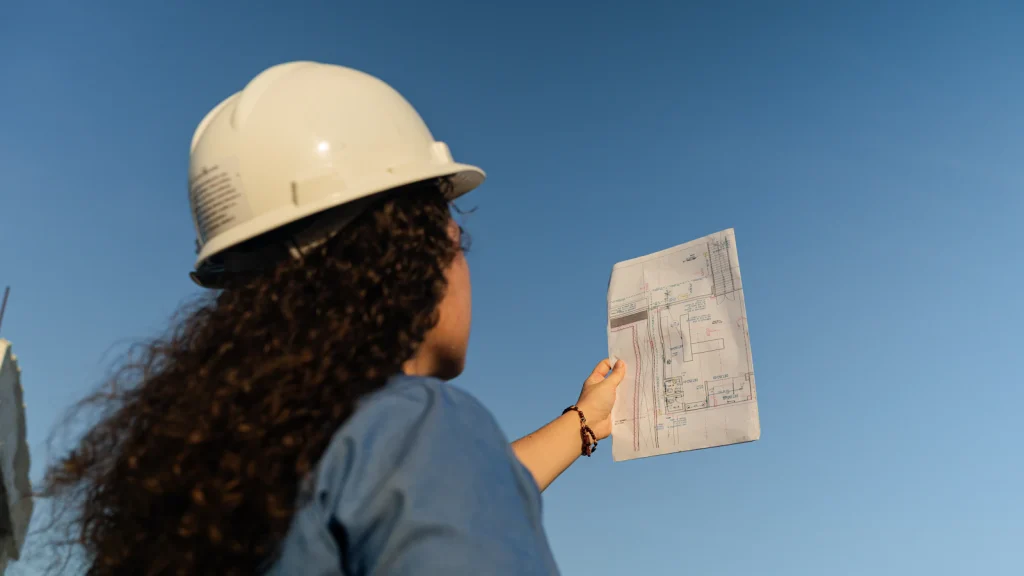 Construction professional in a hard hat reviewing documents on site