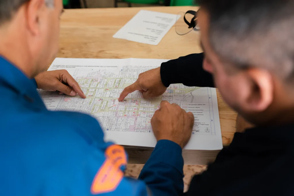 Two engineers reviewing and pointing at a printed plan on a table