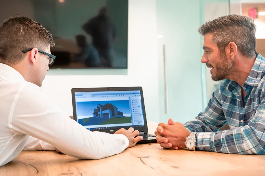 Two construction professionals reviewing a building project on a laptop in a meeting