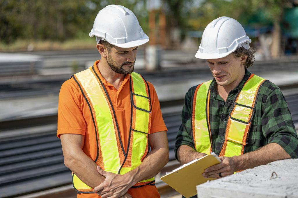 Two construction workers in hi-vis reviewing site documents together