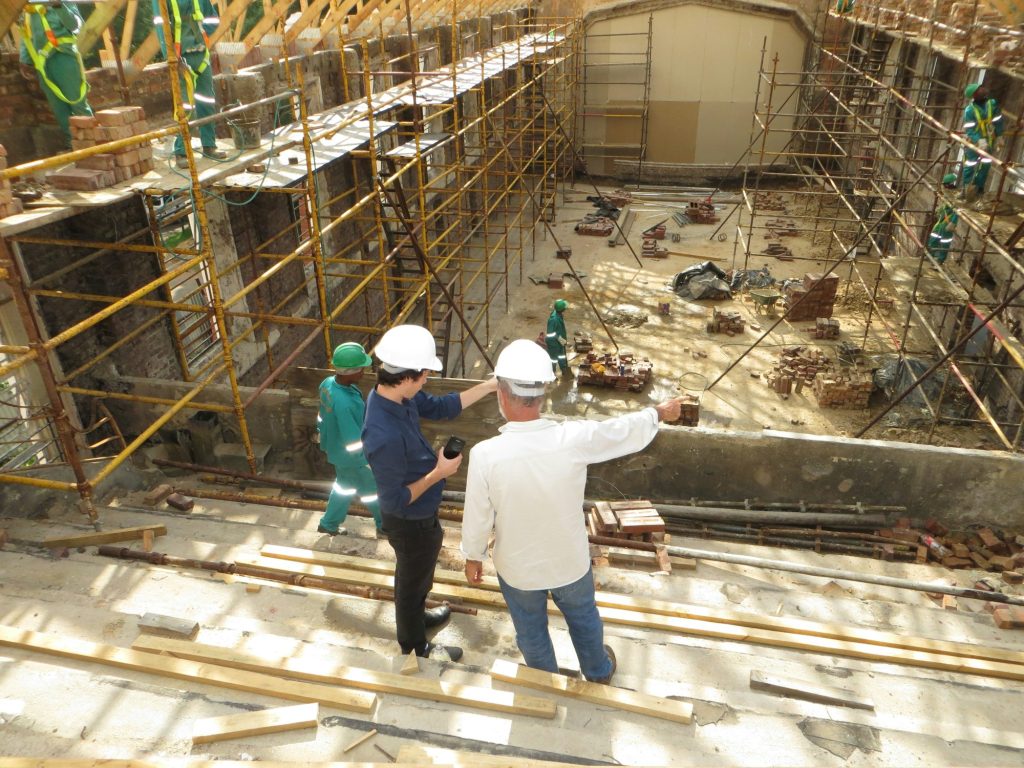 Two site professionals in hard hats inspecting work on a construction site with scaffolding