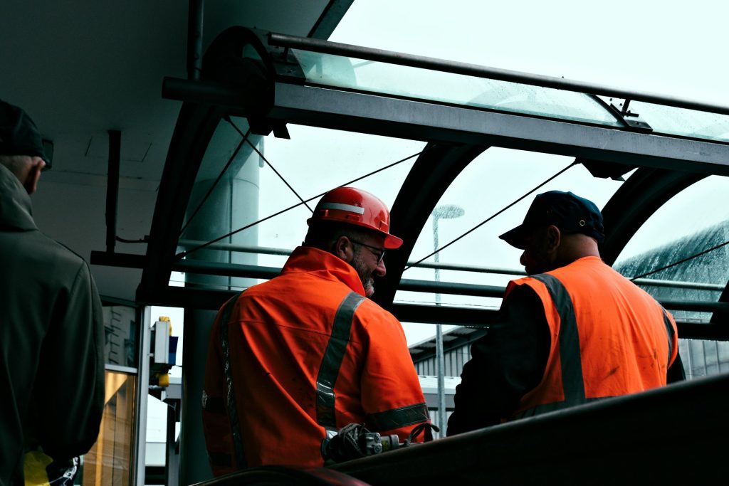 Two construction workers in orange hi-vis discussing work on site